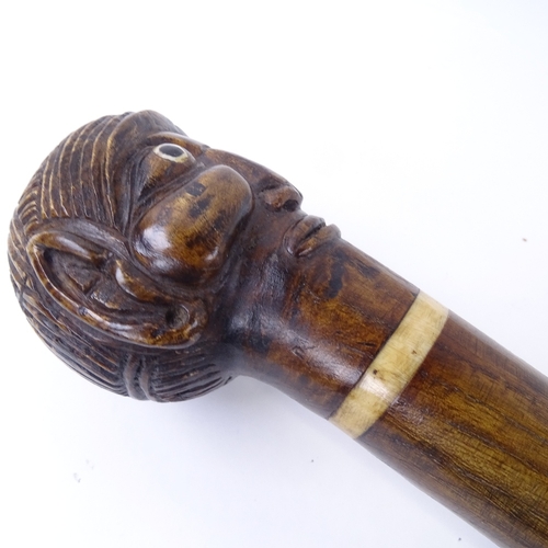 128 - A 19th / 20th century carved head walking cane, possibly made from a staff, 86cm.