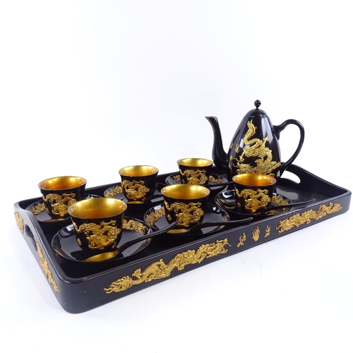 145 - A Chinese gilt black lacquer tea set, with relief dragon decoration, tray 47cm x 27cm.