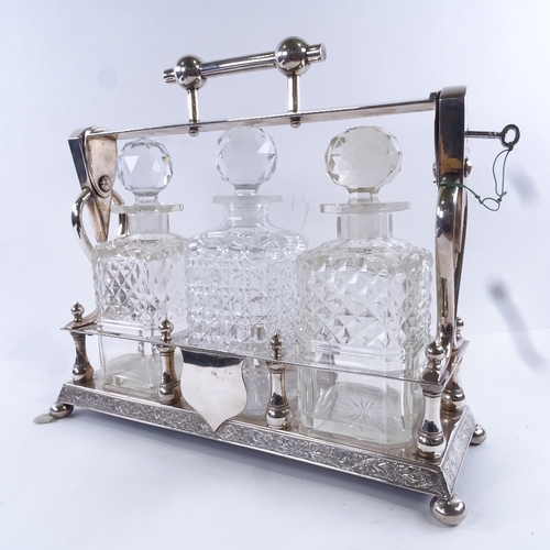 94 - A Victorian electroplate 3 bottle tantalus, containing square cut glass decanters with stoppers, hei... 
