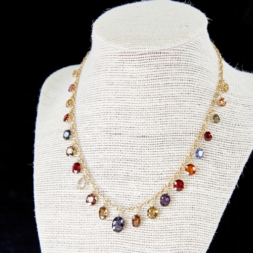 1100 - An Edwardian unmarked yellow metal gem set fringe necklace, set with graduated oval-cut gemstones, i... 