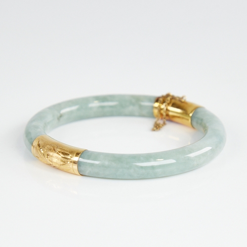 1108 - A Chinese polished jade hinged bangle, with engraved 14ct gold mounts, band width 8.2mm, internal di... 