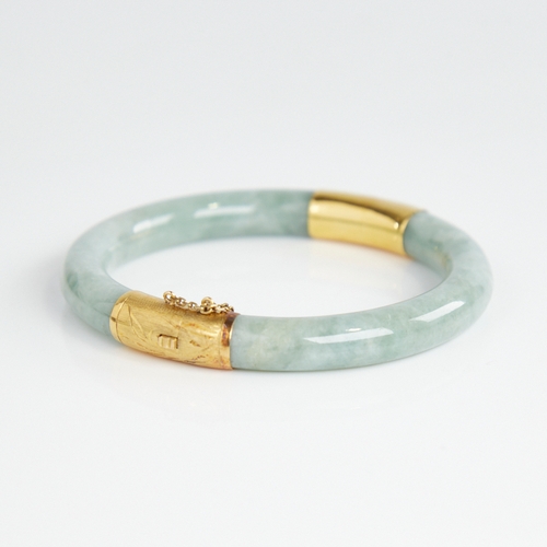 1108 - A Chinese polished jade hinged bangle, with engraved 14ct gold mounts, band width 8.2mm, internal di... 