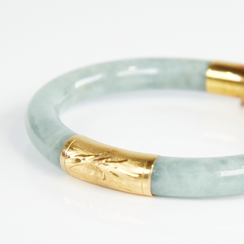 1108 - A Chinese polished jade hinged bangle, with engraved 14ct gold mounts, band width 8.2mm, internal di... 