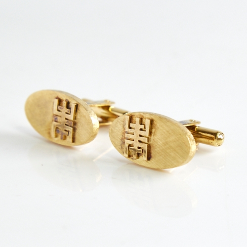 1162 - A pair of Bruneian 14ct gold cufflinks, oval panels with crosshatch decoration and applied character... 