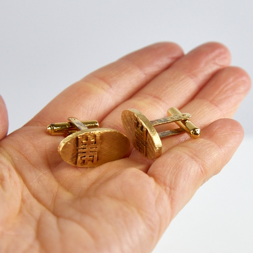 1162 - A pair of Bruneian 14ct gold cufflinks, oval panels with crosshatch decoration and applied character... 