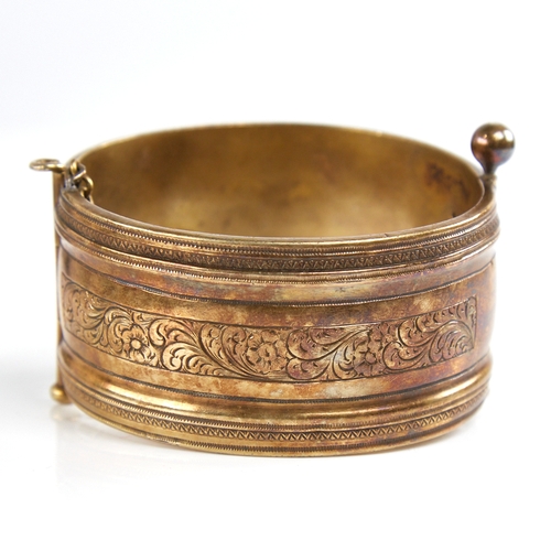 1201 - A 19th century unmarked silver? gilt hinged bangle, engraved floral panels, band width 32.7mm, inter... 