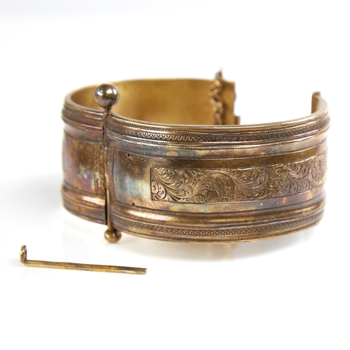 1201 - A 19th century unmarked silver? gilt hinged bangle, engraved floral panels, band width 32.7mm, inter... 