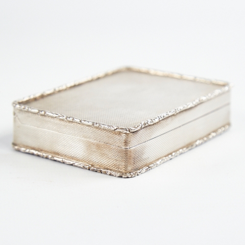 1217 - A George V silver snuffbox, plain rectangular form with cast floral border and allover engine turned... 