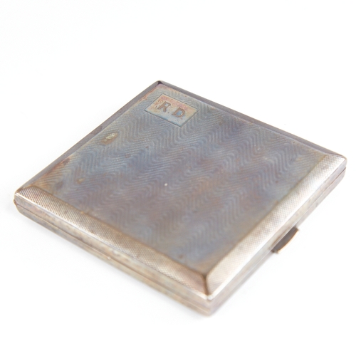 1235 - A George V Art Deco silver cigarette case, square form with wavey engine turned decoration and gilt ... 