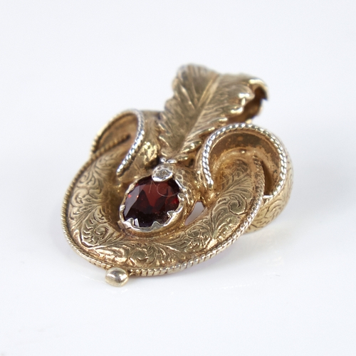 1254 - A Victorian unmarked gold garnet motif brooch, set with oval-cut garnet with allover engraved foliat... 