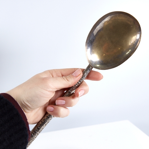 1255 - A large Indian unmarked white metal serving spoon, relief embossed foliate handle, length 26cm, 1.6o... 