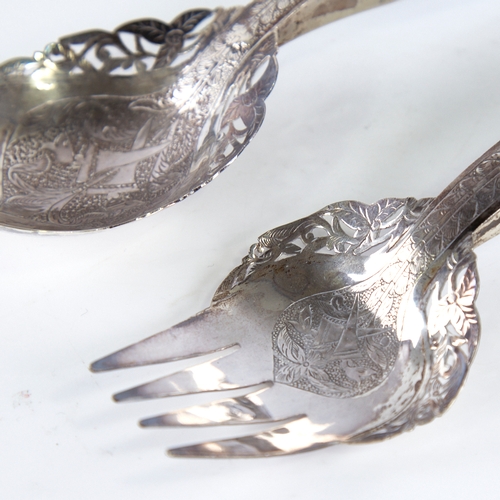 1306 - A pair of Middle Eastern unmarked silver horn-handled salad servers, pierced and engraved floral dec... 