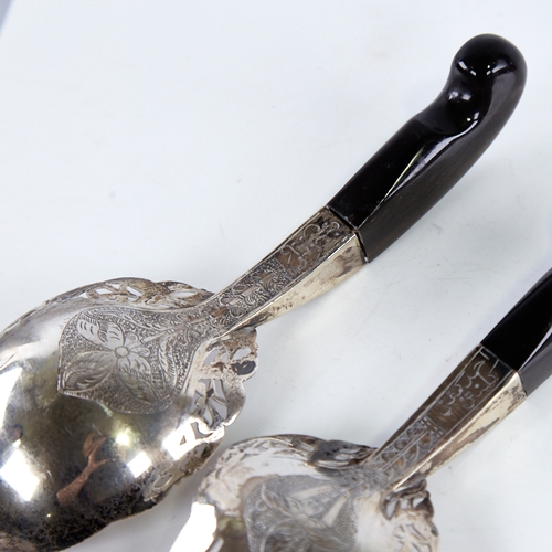 1306 - A pair of Middle Eastern unmarked silver horn-handled salad servers, pierced and engraved floral dec... 