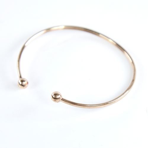 1335 - An unmarked gold torque bangle, tests as 9ct, band width 2.5mm, internal length 53mm, internal heigh... 