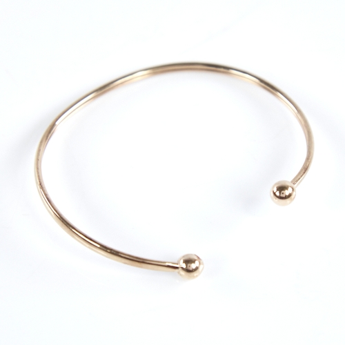 1335 - An unmarked gold torque bangle, tests as 9ct, band width 2.5mm, internal length 53mm, internal heigh... 