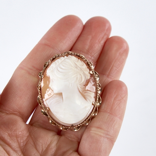 1369 - A mid-20th century relief carved shell cameo brooch, depicting female profile, in 9ct gold twist fra... 