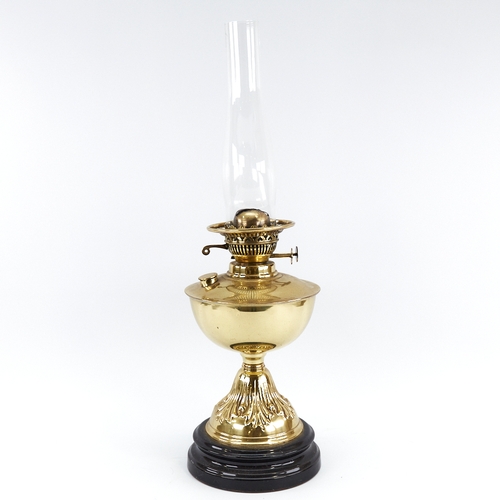 313 - A Vintage embossed brass oil lamp on black ceramic base, with glass chimney, height to fitting 32cm