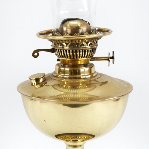 313 - A Vintage embossed brass oil lamp on black ceramic base, with glass chimney, height to fitting 32cm