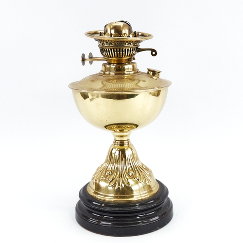 313 - A Vintage embossed brass oil lamp on black ceramic base, with glass chimney, height to fitting 32cm