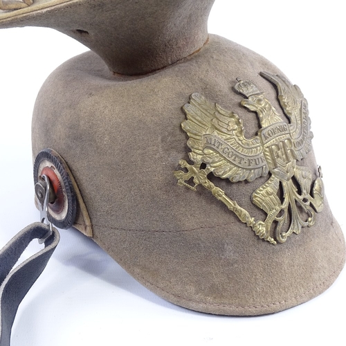 244 - A German felt military helmet with embossed brass crest, replacement leather chin strap