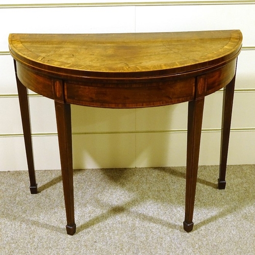 235 - A George III mahogany demilune fold over card table, with tapered legs and spade feet