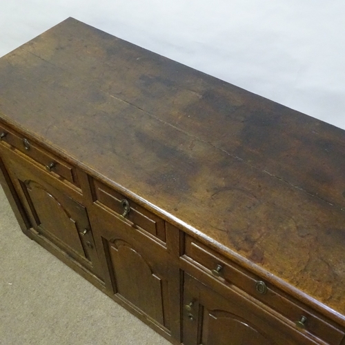 370 - An 18th century oak dresser base, with fielded panelled cupboards and frieze drawers, length 146cm, ... 