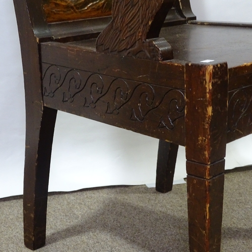 382 - A Nordic Arts and Crafts stained pine elbow chair, with relief carved Viking back panel, eagle desig... 