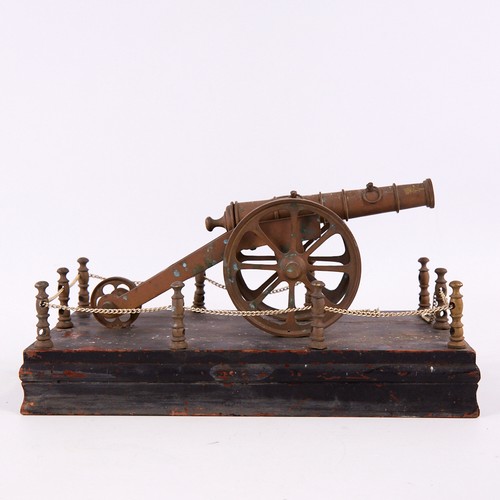 148 - A 19th century style bronze cannon, on painted wood base with chain guard surround, base 31cm long.