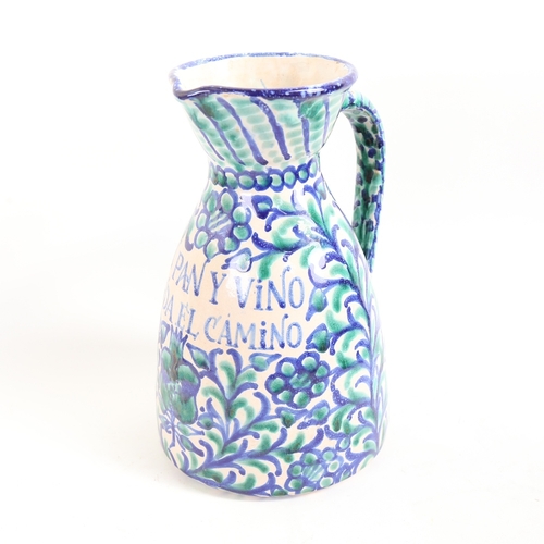 64 - A Spanish faience glazed pottery wine jug, with allover painted decoration and inscription 