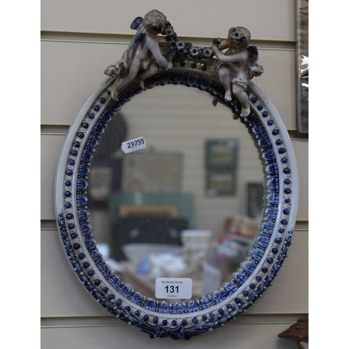 131 - An early 20th century Continental porcelain-framed oval cherub wall mirror, overall height 34cm