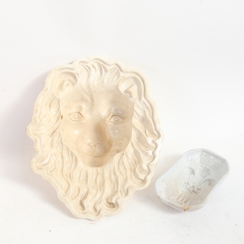 73 - An 18th century Creamware lion mask jelly mould, length 25cm, and another smaller fleur-de-lis mould... 