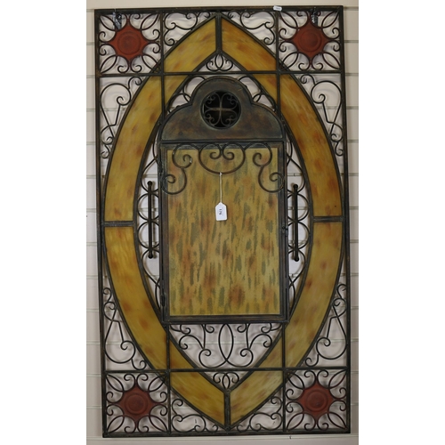 176 - A large wrought-iron and yellow stained glass candle stand wall panel, with allover pierced scrolled... 