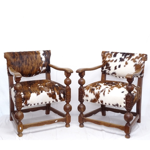 1886 - A pair of Baronial style oak elbow chairs, upholstered in cowhide