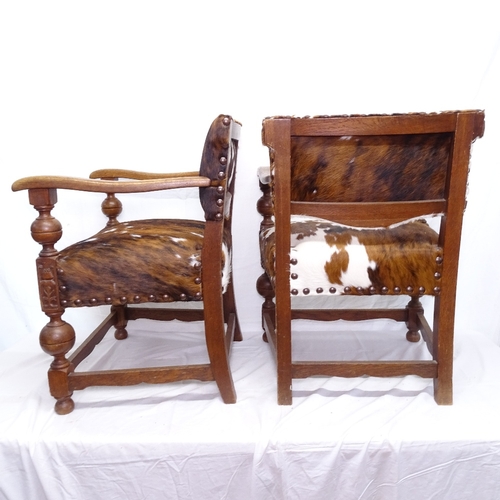 1886 - A pair of Baronial style oak elbow chairs, upholstered in cowhide