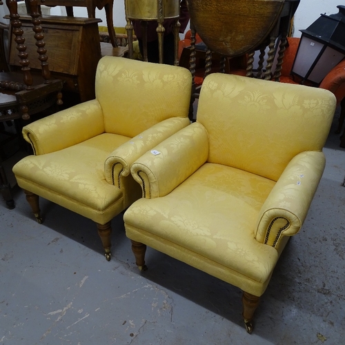 2033 - A pair of Howard style upholstered rollover armchairs, on turned legs, and brass casters