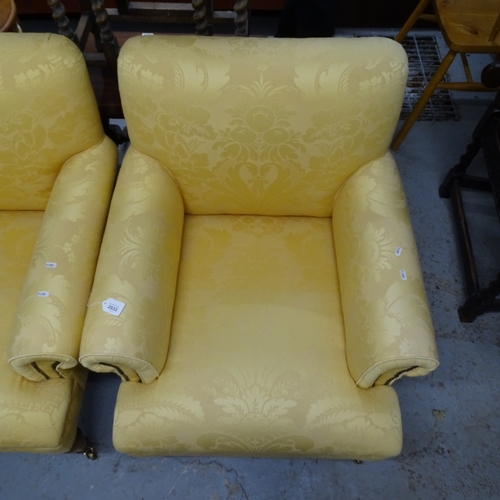 2033 - A pair of Howard style upholstered rollover armchairs, on turned legs, and brass casters