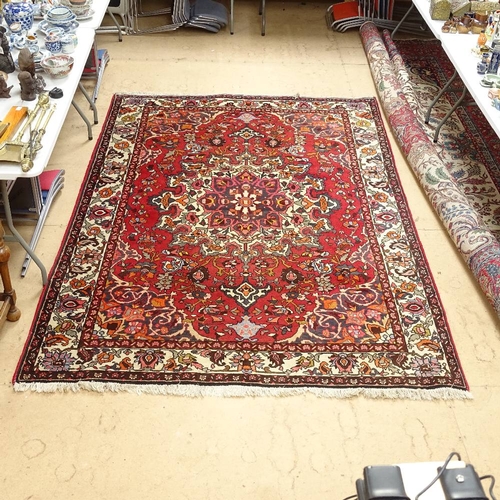 1947 - A handmade red ground Heriz wool rug, 300cm x 204cm