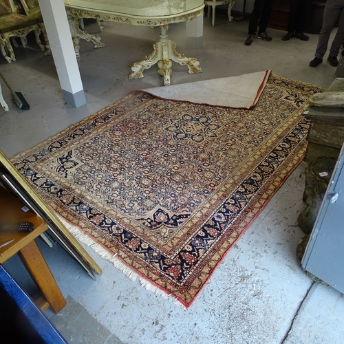 1977 - A red ground Tabriz design carpet, with symmetric pattern borders, 335cm x 225cm