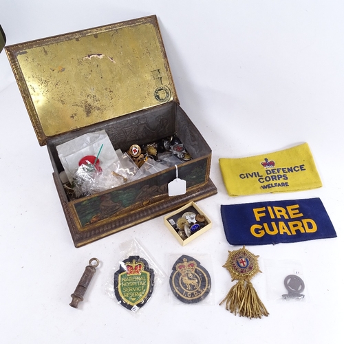 173 - Various military badges, arm bands in a biscuit tin