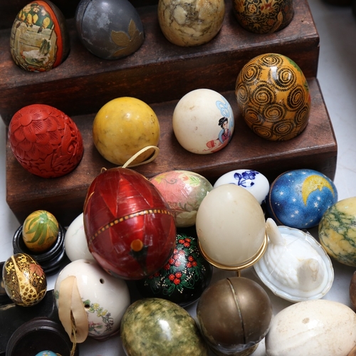 585 - A large quantity of various egg ornaments, including lacquered, china, hardwood, hardstone etc