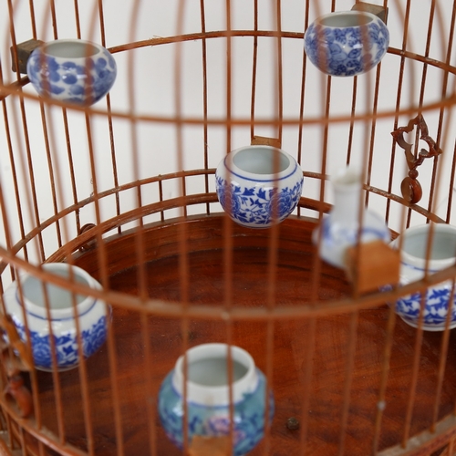 844 - An Oriental stained bentwood birdcage with porcelain feeder bowls, height 40cm