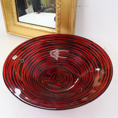 911 - A rectangular gilt-framed wall mirror, and a red and black Art glass bowl, diameter 40cm (2)