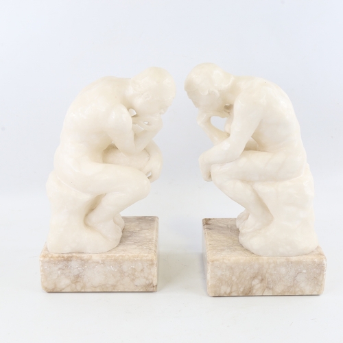 106 - A pair of carved alabaster crouching figures on marble block plinths, height 29cm