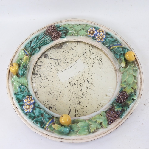 138 - A Continental faience pottery circular wall mirror, relief moulded fruit decorated surround, no fact... 