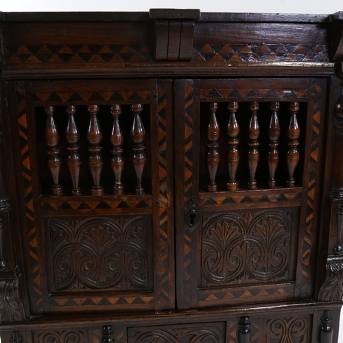 24 - A small 19th century carved and panelled oak wall-hanging cupboard, with spindled panelled doors, a ... 