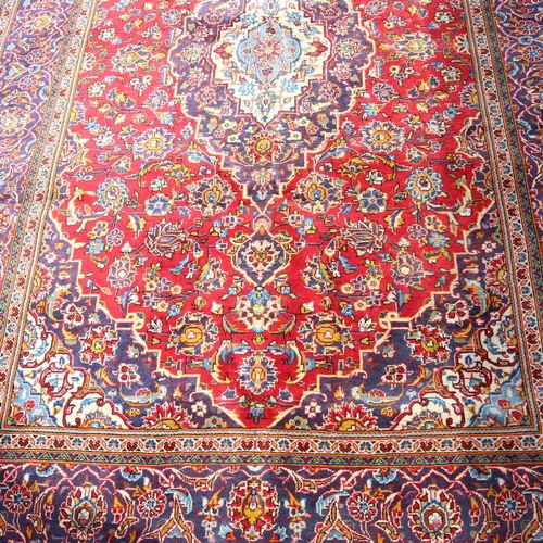 442 - A large red ground Kashan wool rug, floral decoration with border, 298cm x 200cm