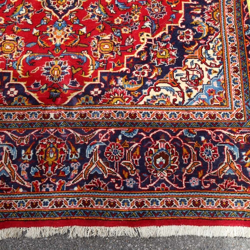 442 - A large red ground Kashan wool rug, floral decoration with border, 298cm x 200cm