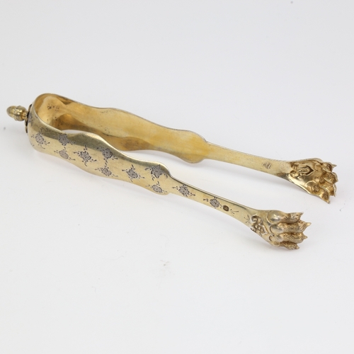 1111 - A pair of 19th century French silver-gilt lion paw sugar tongs, bright-cut engraved floral decoratio... 