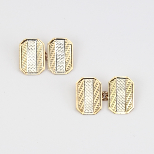 1118 - A pair of 9ct gold cufflinks, canted rectangular form with engine turned decoration, panel length 16... 