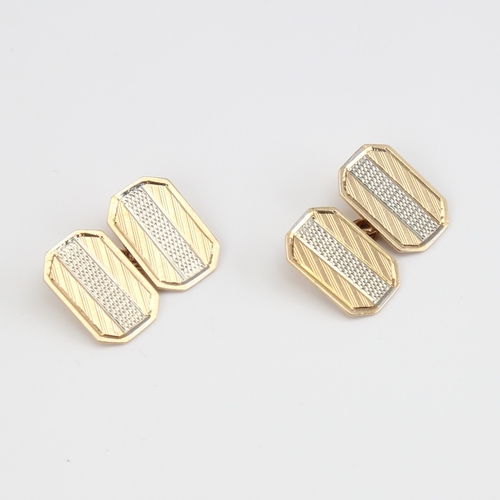 1118 - A pair of 9ct gold cufflinks, canted rectangular form with engine turned decoration, panel length 16... 